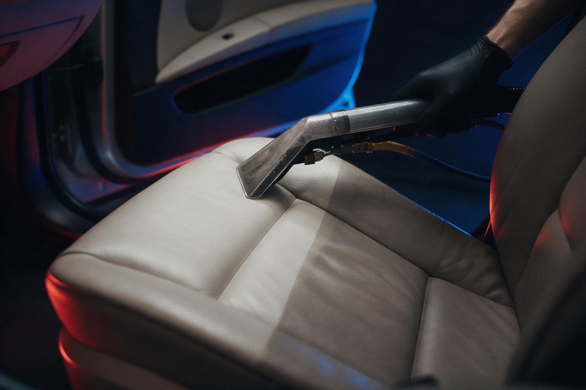 Extratora limpando banco de couro claro em um interior de carro (imagem ilustrativa)